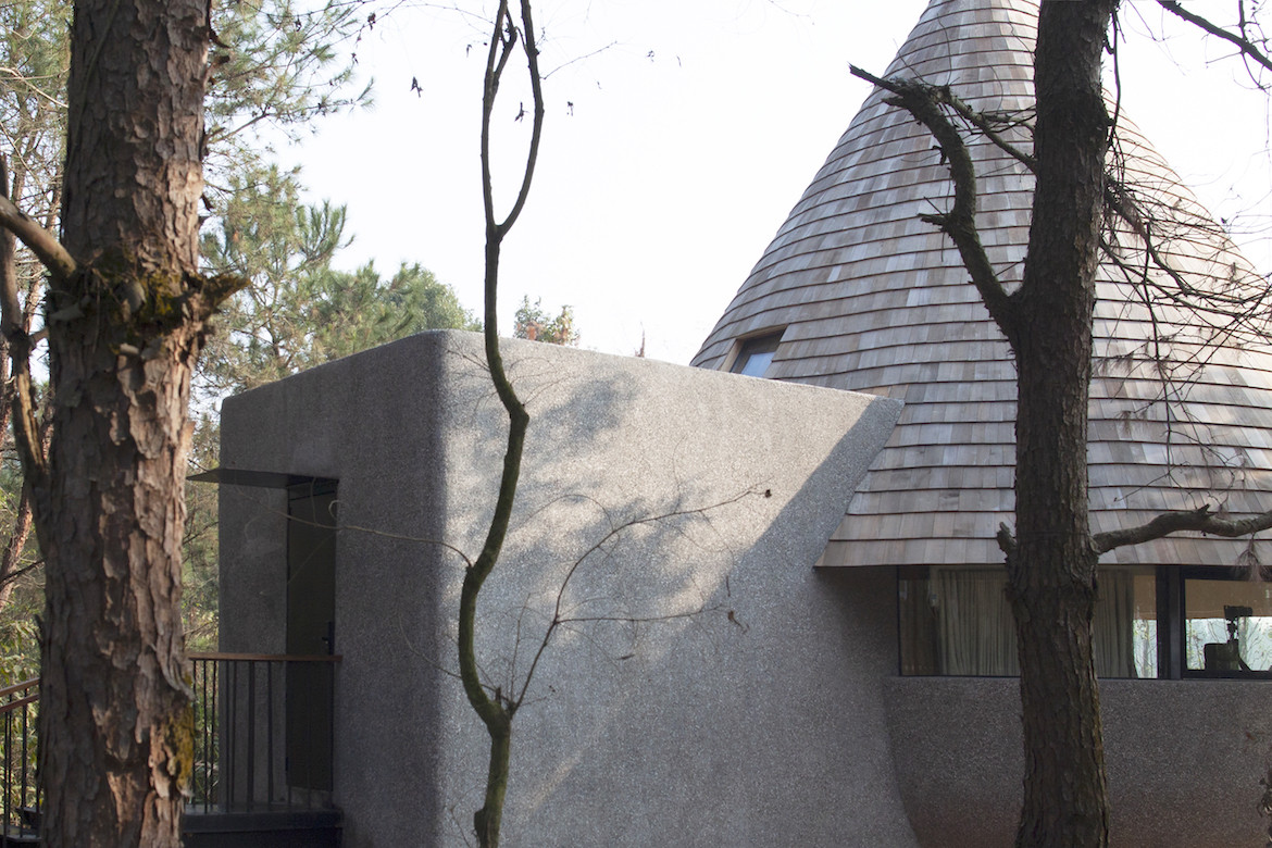 Exterior view of the shingled roof and grey cement wall of The Mushroom by ZJJZ