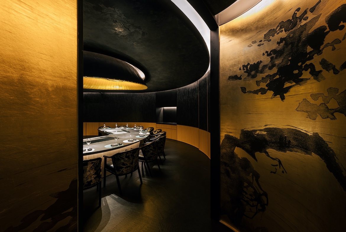 Chair are seated around a large curving table under golden lights in God of Teppanyaki large dining room.
