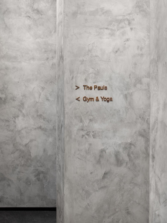 Gold writing on a grey wall points to "Gym & Yoga" one way and "The Pauls" another in The Goodman Group's headquarters by woods bagot