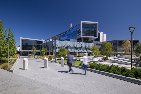 Blurry figures walk towards the large facade of the Royal Adelaide Hospital by DesignInc.