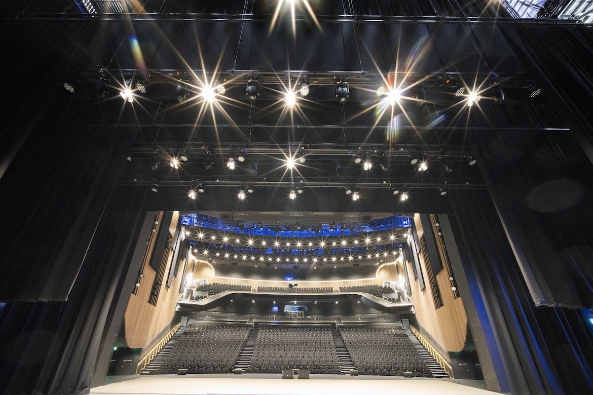 The main stage of the Sydney Coliseum Theatre with timber edges, black seating and black curtains.