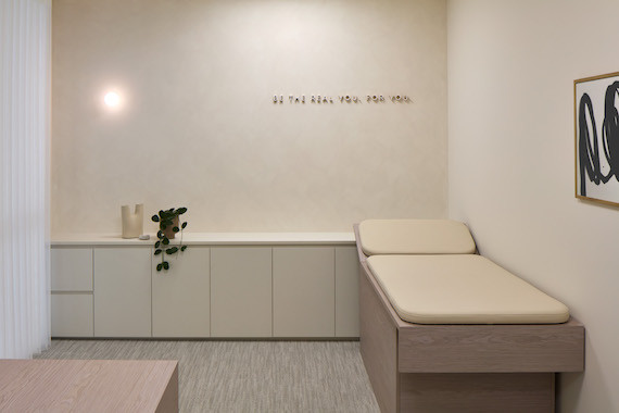 A beige medical bed under the words 'Be the real you. For you' in New Me medical centre by Rezen Studio.