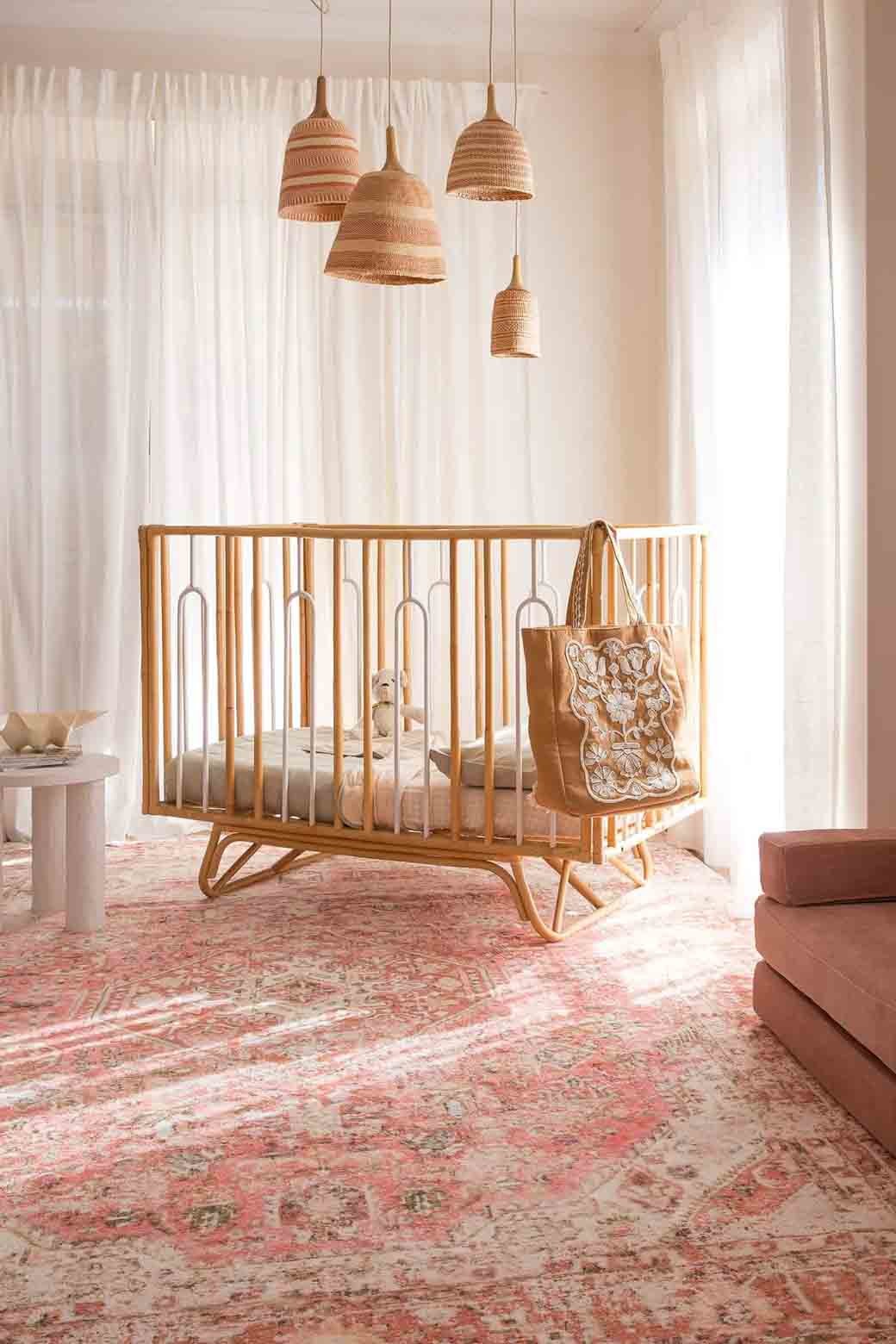 peach pink persian rug and cot in nursery beige colour scheme white room hanging lights