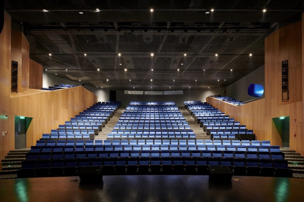 500 navy blue seats in the Pinge Bibliotheater main theatre, surrounded by wooden walls.