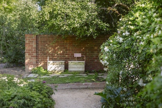 Two seats made from the Heidi's leftover limestone, in front of a brick wall in the Healing Garden.