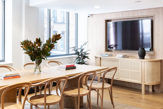 A long brown conference table with a TV at the end in the WeWork office.