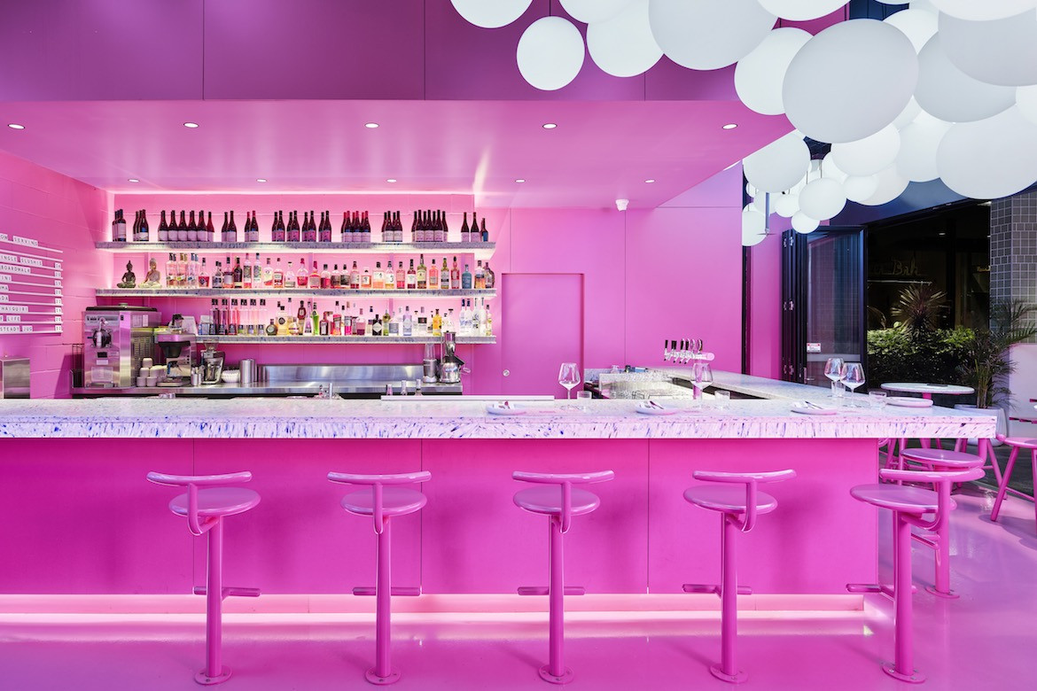 A bar lined with pink powder-coated derlot stools interior of Ping Pong.