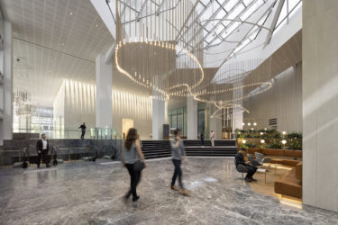 People walk underneath the sculptural hanging lighting in the lobby of 600 Bourke Place.