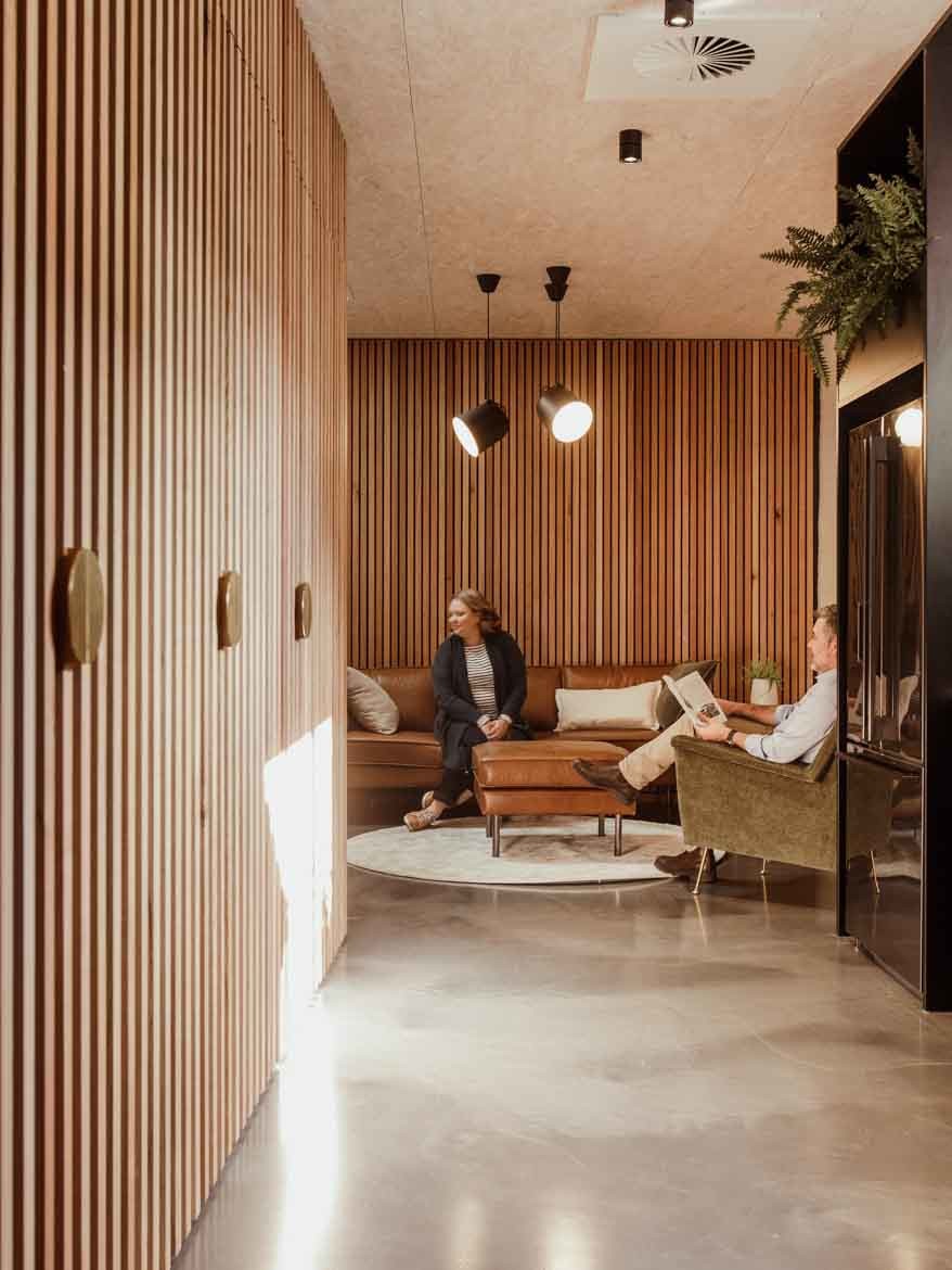 Two people sit in a relaxing area surrounded by Tasmanian Oak wood battens in the ERA office, Hobart, by Cumulus.