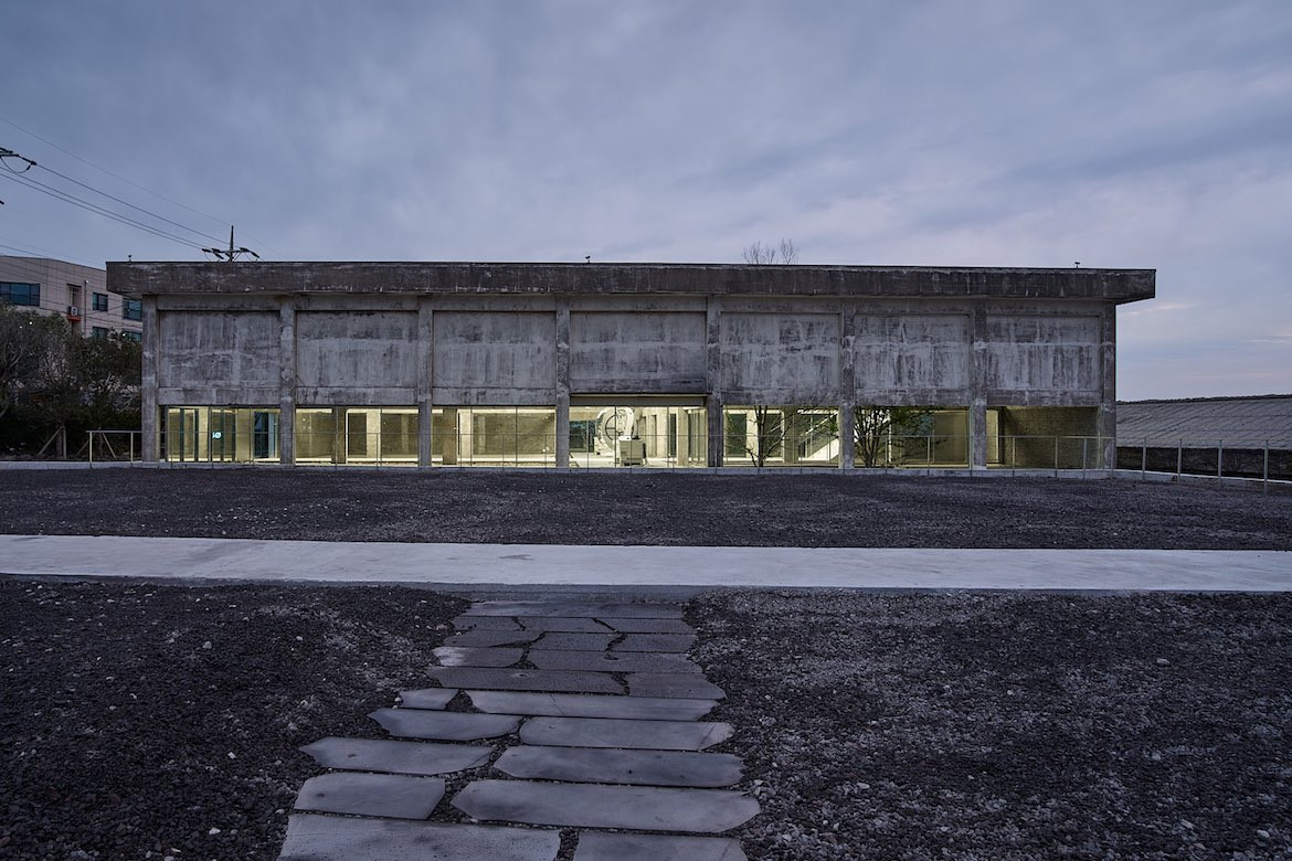 The exterior concrete building of Gongbech at dusk, with warm light emanating from the windows.