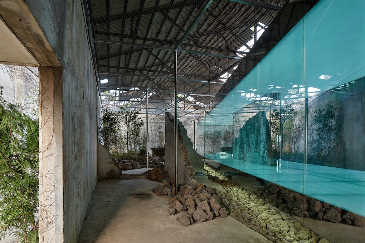 A blue-tinged glass box placed at an angle among crumbling walls in Gongbech.