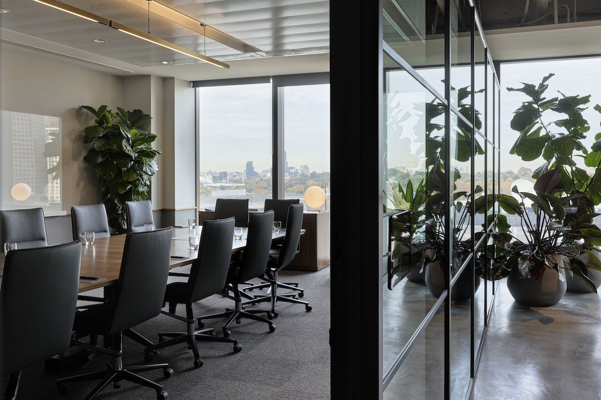 Empty desk chairs surround a long conference table.