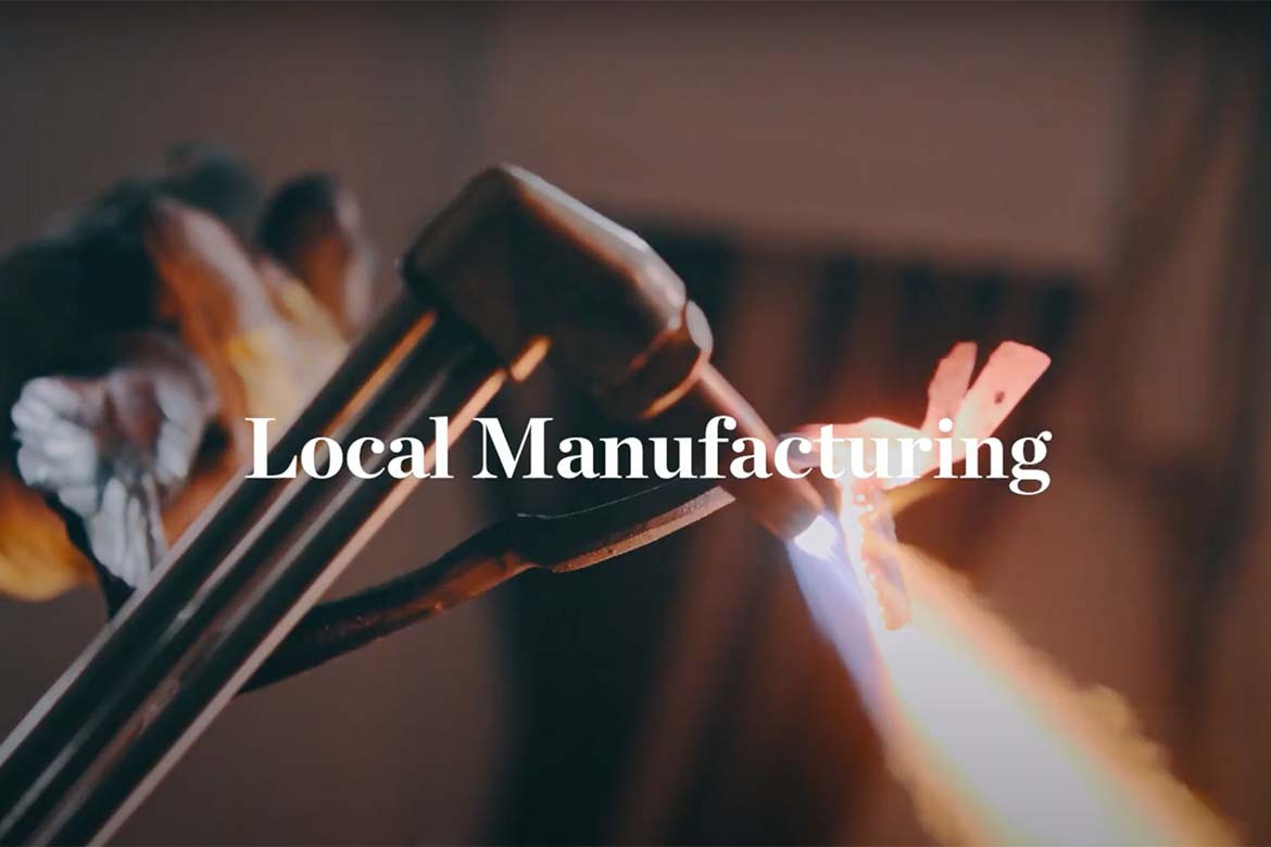 A maker using a blow torch with the words Local Manufacturing embedded on top of the image.