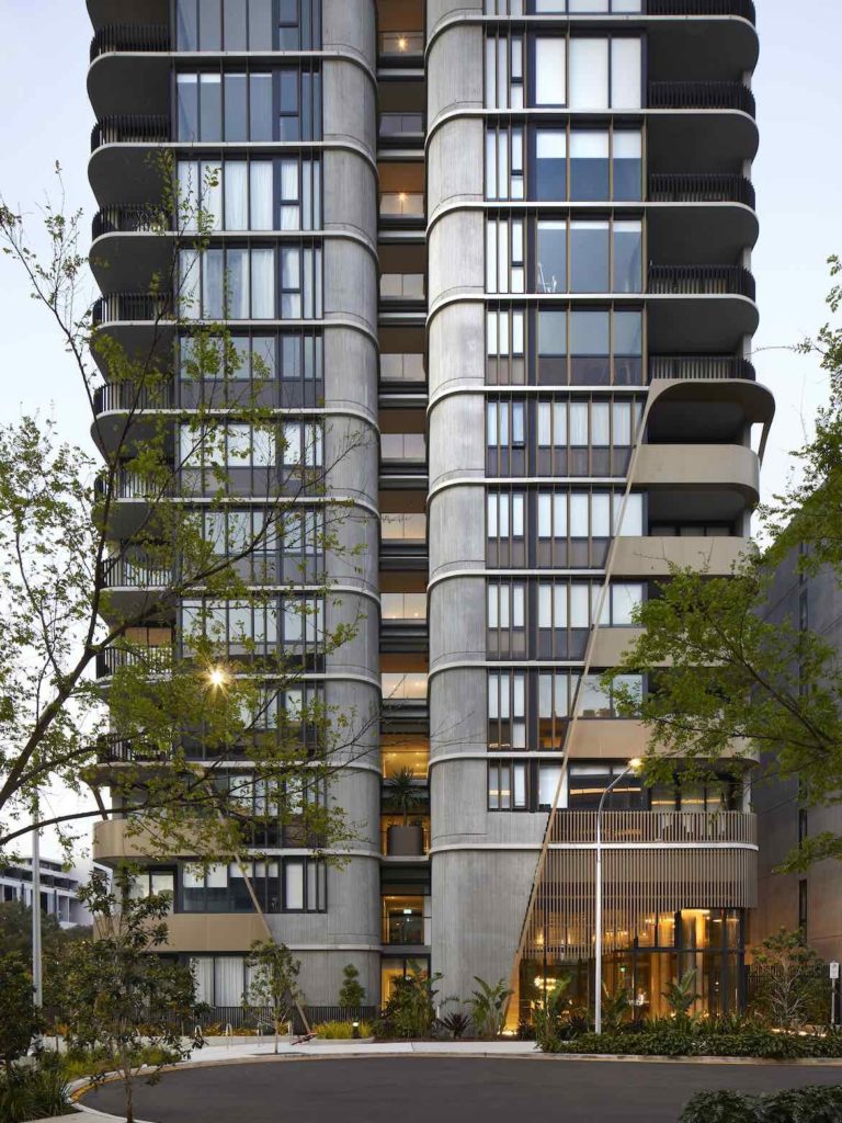 The tall exterior of Waterfall by Crown group, displaying rounded edges, concrete, greenery and wood panelling.