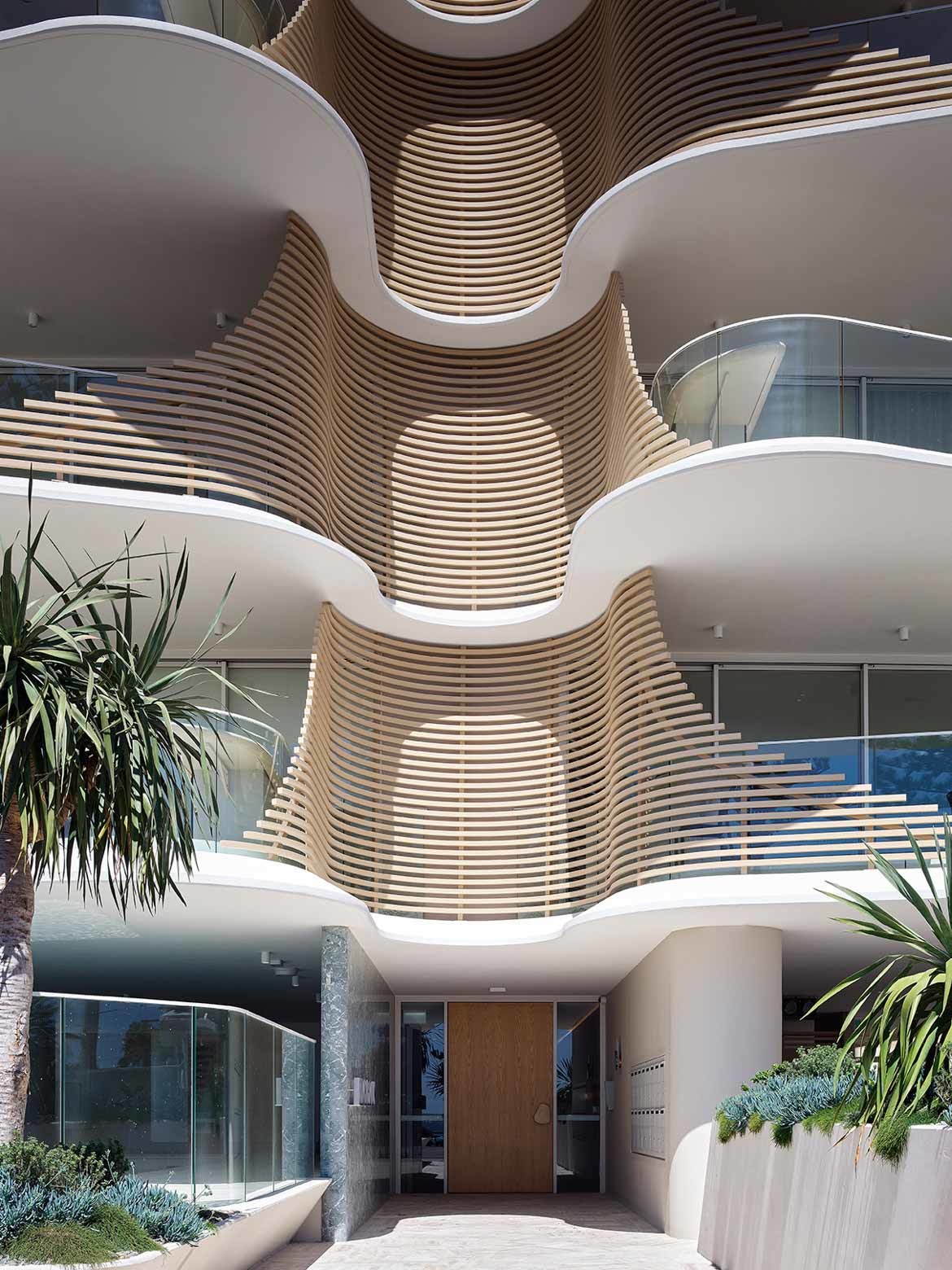 Contrast of wood panelling between curving white levels create the facade of Norfolk by Koichi Takada Architects.