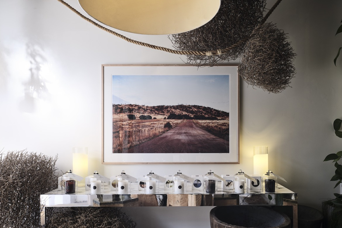 A photography and tumbleweeds hang above a row of The Raconteur candles.