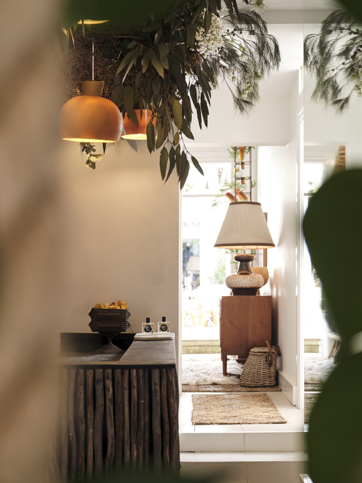 Beeswax lampshades hang down from the ceiling among eucalyptus leaves.