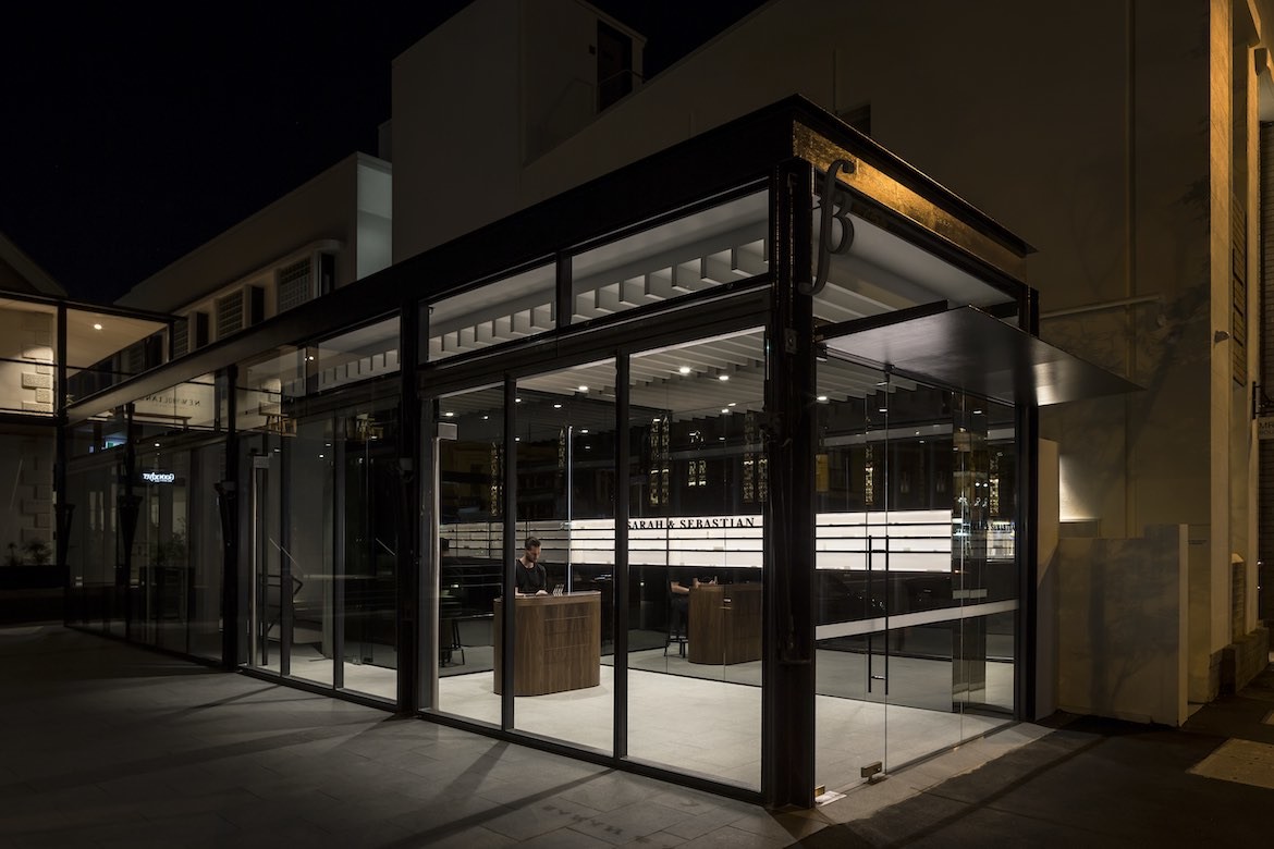 The exterior corner of a Sarah & Sebastian retail store by Landini Associates, photographed at nighttime.
