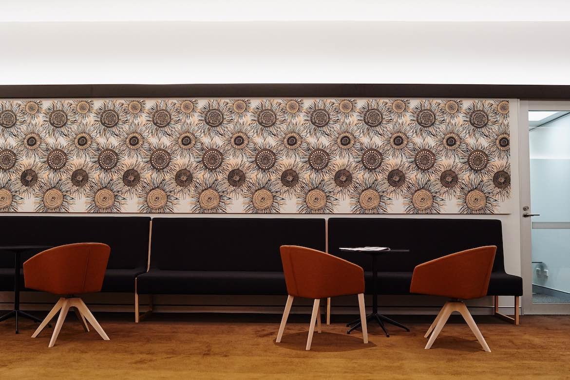 Navy blue bench seating, a tan carpet and red arm chairs in the Darwin Innovation Hub by Georgina Wilson Associates.