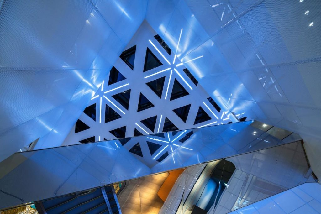 A view towards triangular windows in the ceiling of ShuiFa Information Town Industrial Exhibition Center, with one metallic bridge in the foreground.