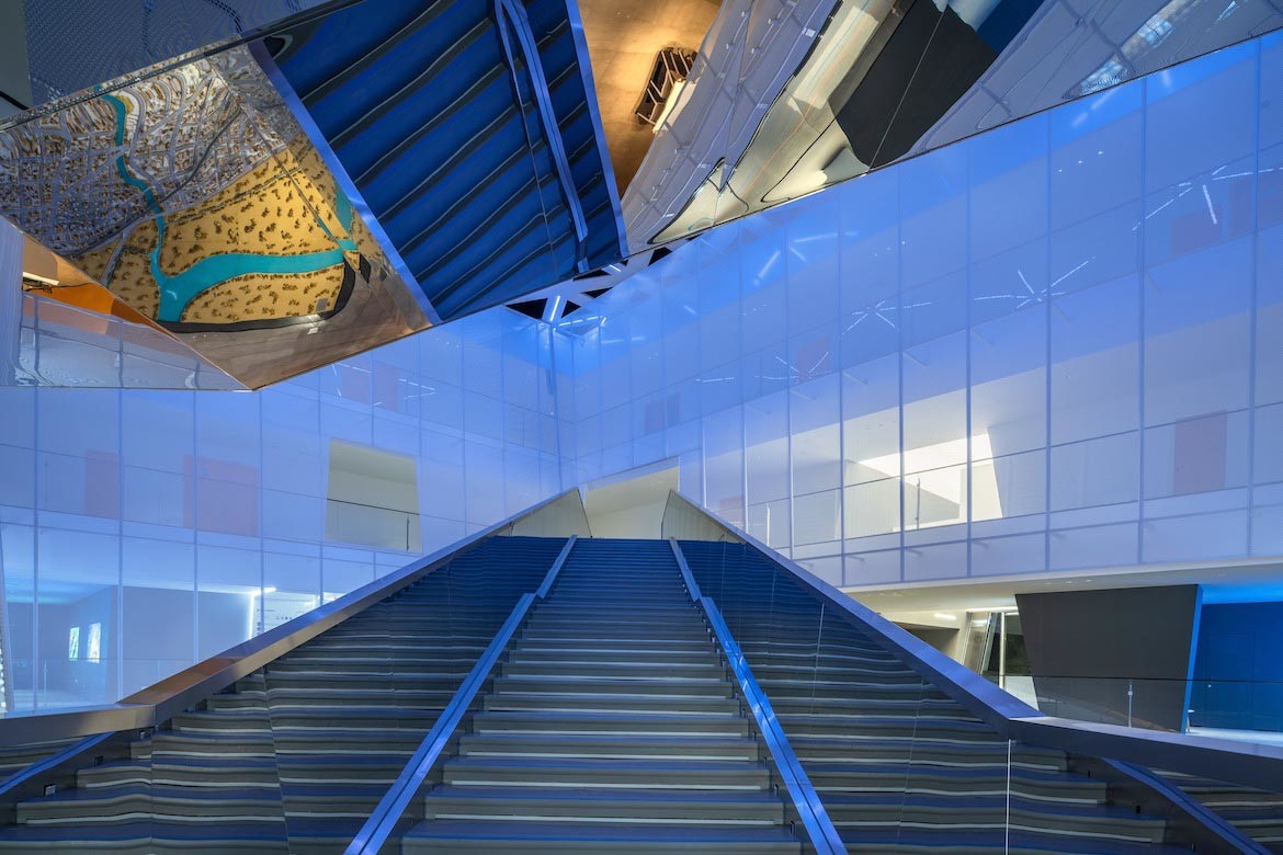 Stairs leading towards the perforated walls of the upper level of ShuiFa Information Town Industrial Exhibition Center.