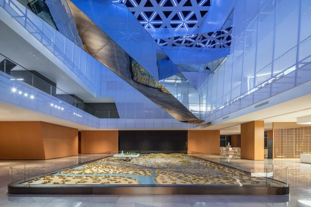 A miniature town on the ground floor of ShuiFa Information Town Industrial Exhibition Center under reflective metallic bridges.