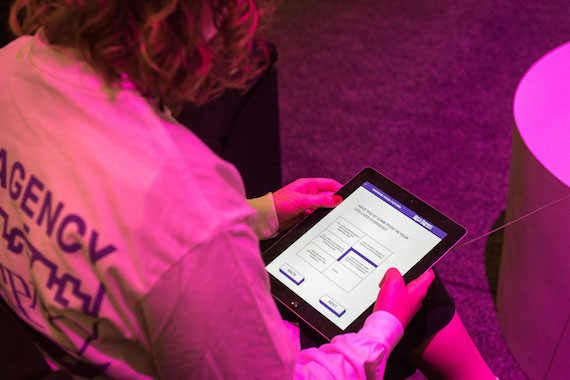 A person answers research questions at the New Agency exhibition.