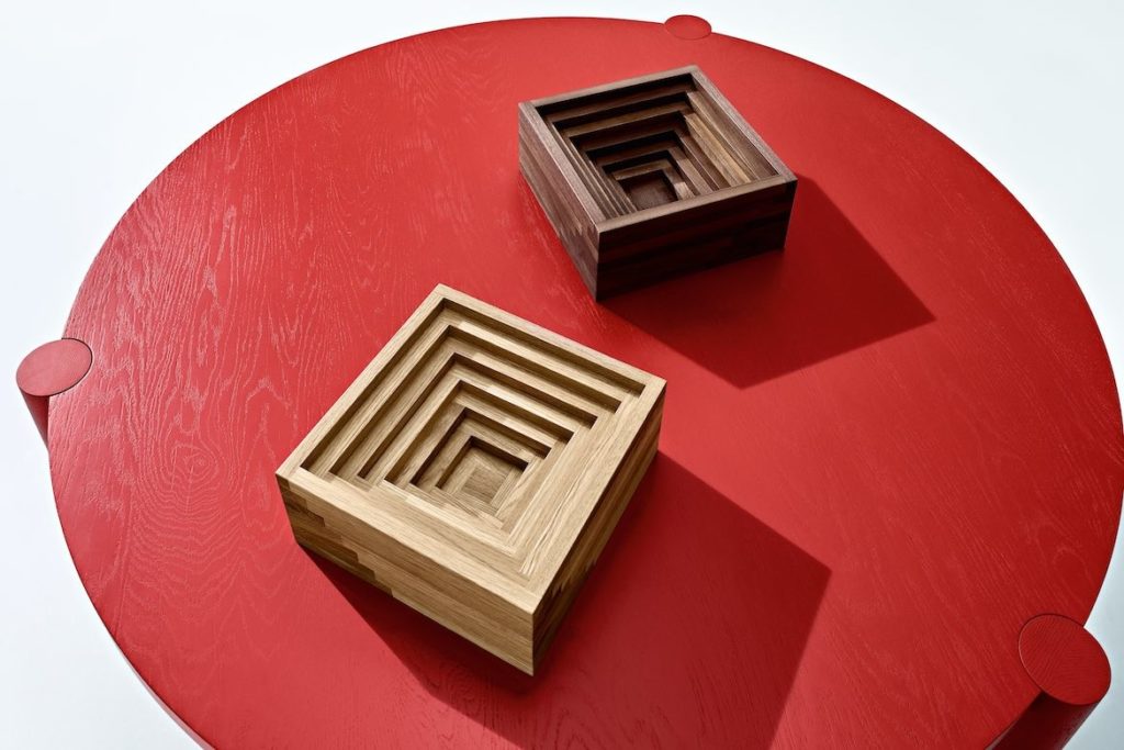 Two ampitheatre-like square bowls in pale and dark wood, on a round red table by Boris Tošić.