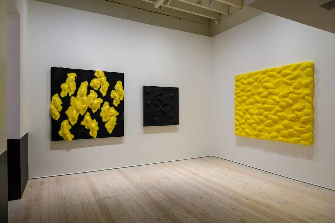 Three yellow and black artworks hanging on the walls of White Rabbit Gallery.