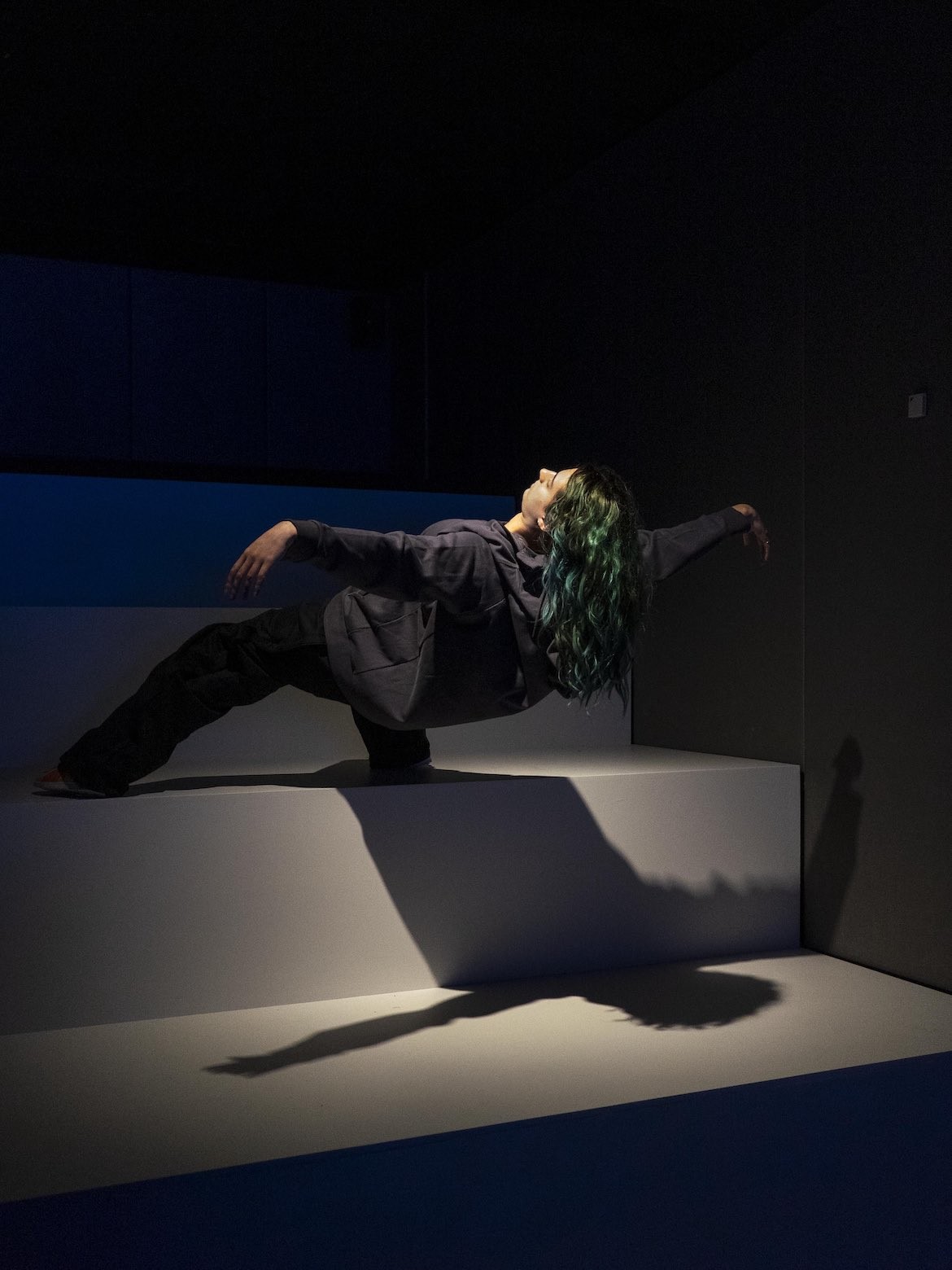 An installation of a lifelike woman sculpture floating on the edge of a stair at White Rabbit Gallery.