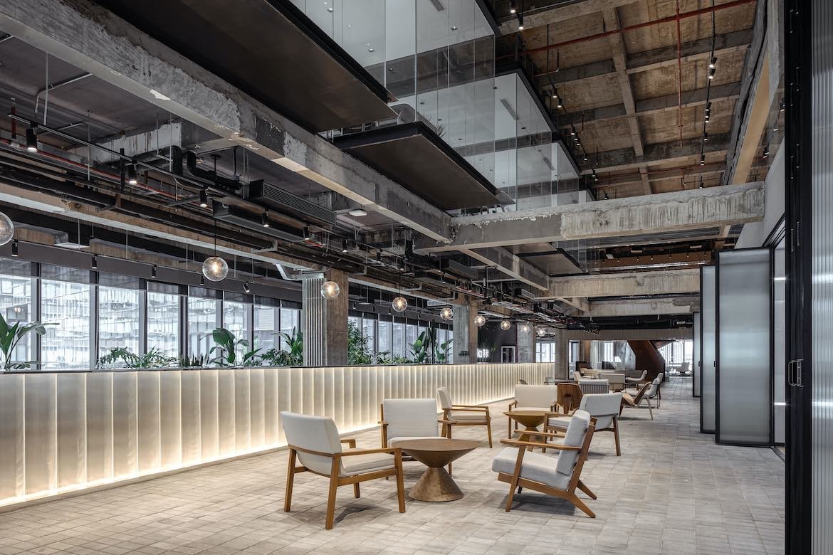 Wooden arm chairs with white upholstery sit in communal spaces of the Yeahka office by JSPA Design.