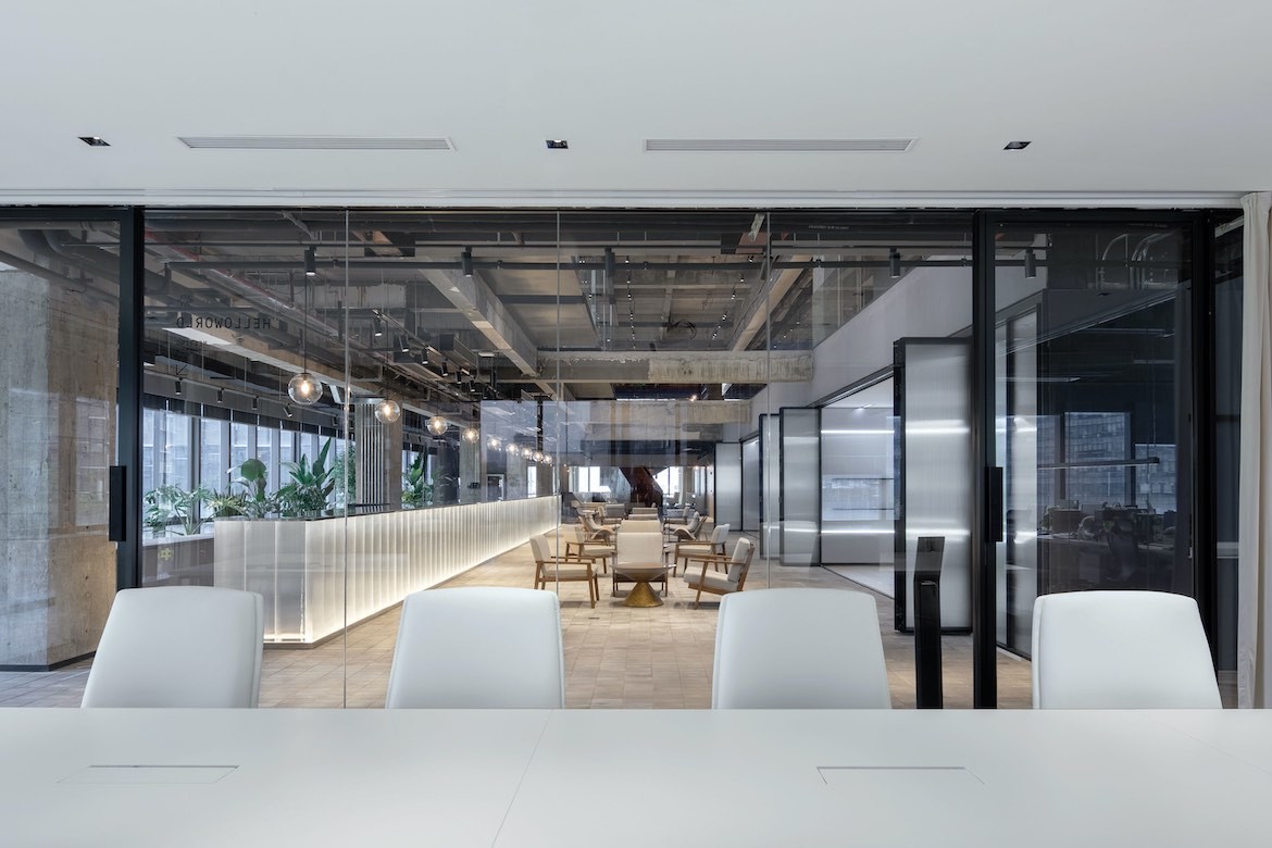 Four white chairs sit along a white desk in a meeting room of the Yeahka office by JSPA Design.